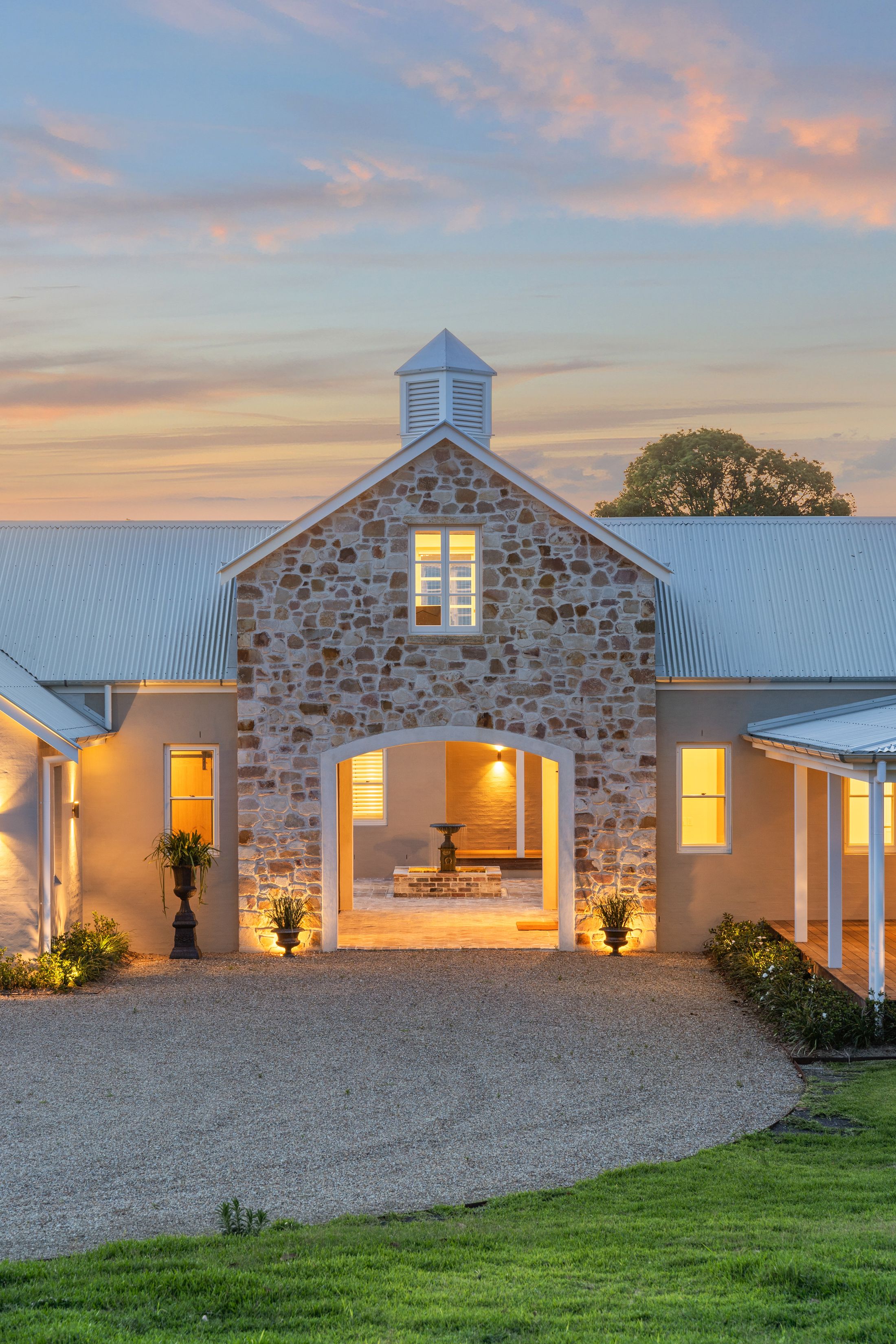 A stone barn and homestead built by SaltyDog Landscaping, lit at dusk