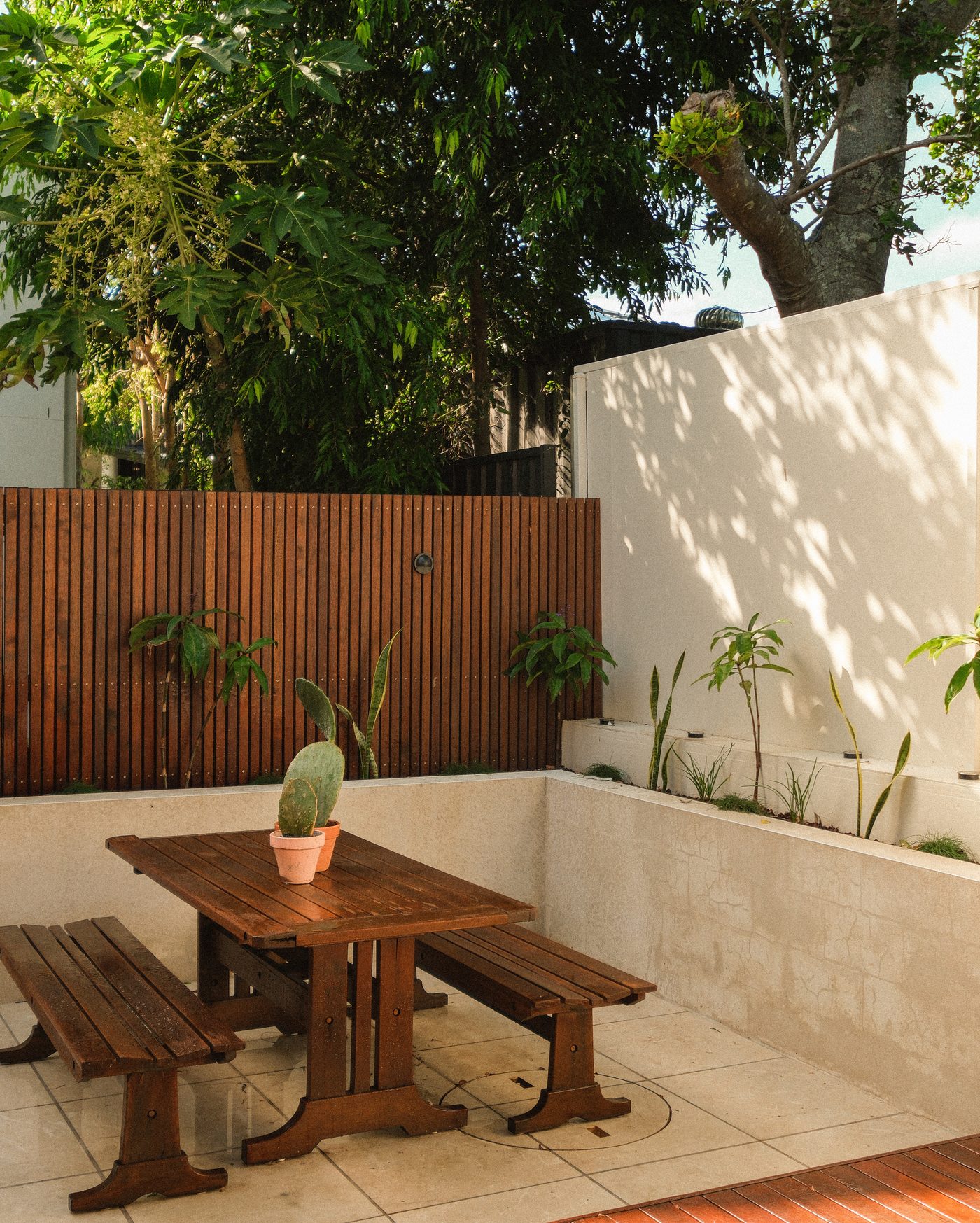 A limestone dining terrace against a battened hardwood fence