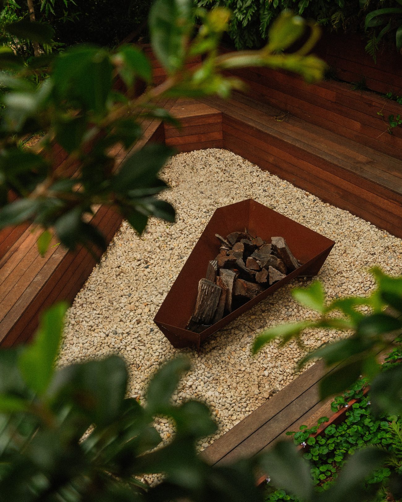 A corten steel fire pit set into white pebbles