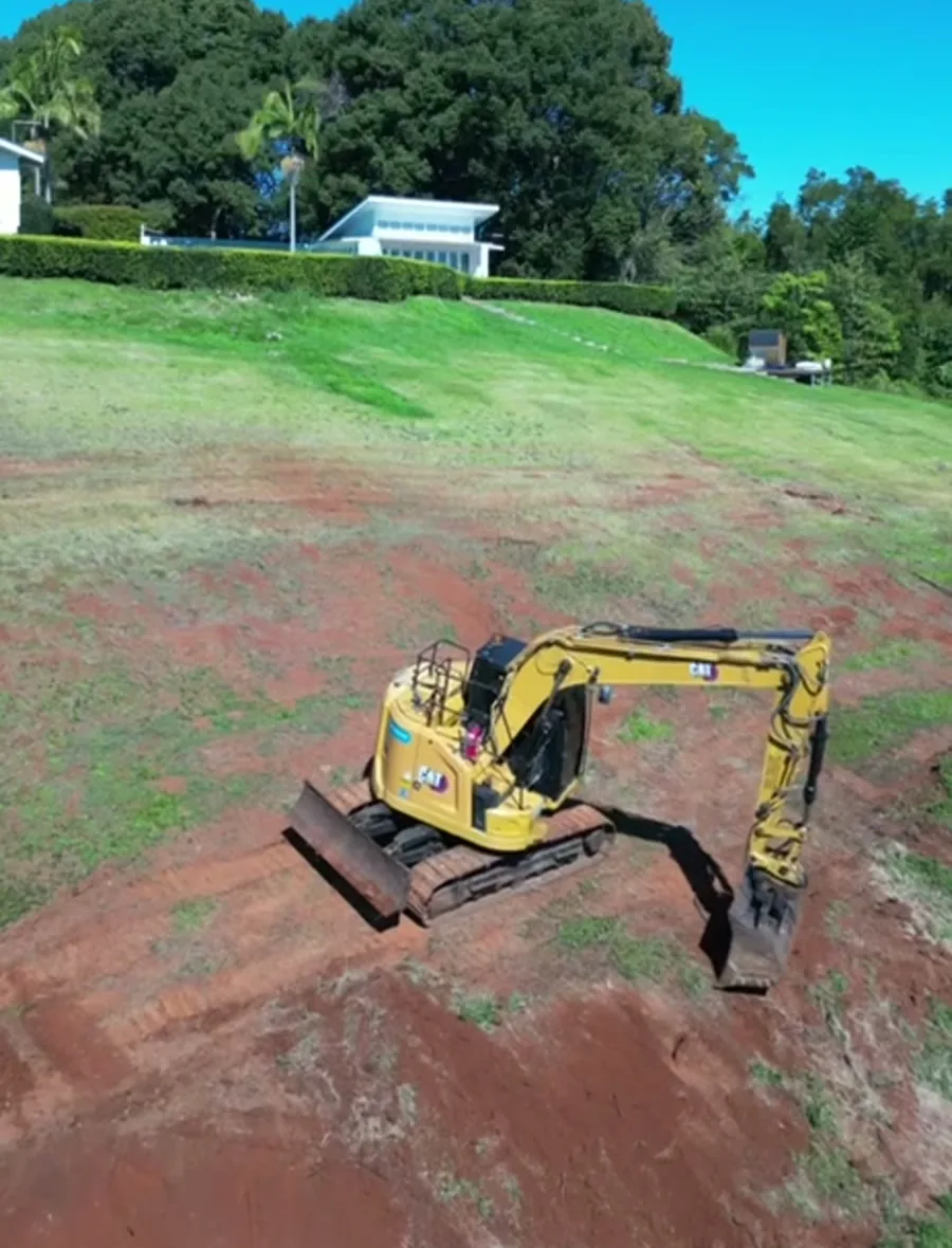 An excavator clearing a hillside site