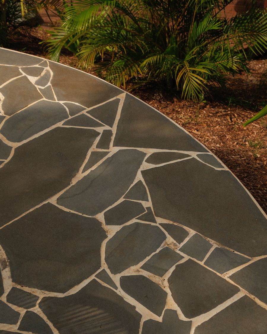 A circle of crazy paving set into mulch and planting